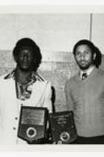 Portrait of two young men holding plaques. Written on verso "Left- Ezra johnson- Top Football player (auc), (Morris Brown Student), Right- Morris Brown Student Top Basketball player (auc)".