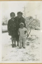 Two girls stand in the snow with a woman.