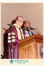 President Hugh Gloster speaking at podium with unidentified person.