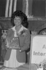 Vivian Malone Jones smiles and holds a plaque given to her at an event.