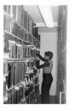 An unidentified woman looks at books in library.