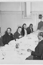 A group of men seated at a large dining table. Written on verso: Minister's conference.