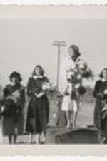Outdoor view of women standing on a podium on a football field.