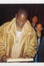 Singer Tyrese Gibson is shown looking at a framed item. Some of the Lowery's grandchildren stand in the background.