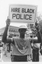 A protester in Decatur, Alabama holds a sign that reads "Hire Black Police". Written on verso: This demonstrator displays a sign calling for one of the black community's demands. Others include hiring of blacks in county government and equal opportunity in employment in the private sector.