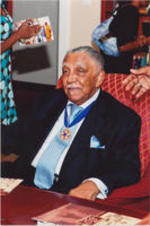 Joseph E. Lowery is shown sitting in a chair at unknown event. He wears his Presidential Medal of Freedom.
