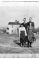 Two women and two men stand in front of several homes.
