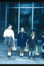 Unidentified children holding baskets on the front steps of an unidentified building.