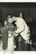 View of man kissing woman with crown. Written on verso: "Dr. Smith gives Miss MBC a kiss- Michelle Patmon 1984-85".