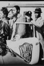 Students enter an Atlanta police car after being arrested for protesting a segregated cafeteria.