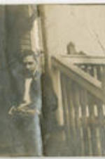 Eugene Dibble sits on steps in front of a house. Written on verso: "Eugene Dibble."