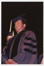 Lou Rawls stands, wearing graduation cap and gown, at the summer commencement.