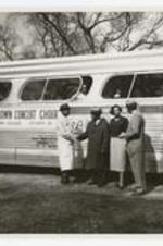 View of three men and a woman standing next to charter bus, on sign "Morris Brown Concert Choir, Morris Brown College Atlanta Ga.".
