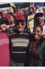 Dr. Walter Boradnax poses with students in the stands of the stadium.