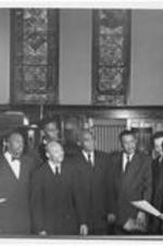 Dr. Harry V. Richardson (holding paper, right) stands in a chapel with a group of men. Written on verso: Student Christian League featuring James Tead, Harlon London and James Washington of present graduating class.
