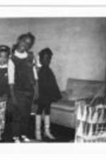 Three unidentified young girls stand in a living room.