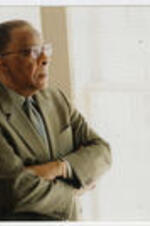 Eldridge McMillan stands near a window. Written on verso: CAU 2001 Eldridge McMillan