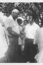 Ralph D. Abernathy is shown shaking hands with an unidentified man during an outdoor event.
