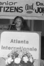 An unidentified woman speaks from an "Atlanta Internationale" podium at an event.