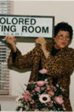Evelyn G. Lowery is shown holding a "Colored Waiting Room" sign from the Nashville, Chattanooga and St. Louis Railway.