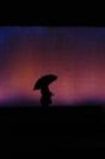 Silhouette view of actors with umbrella on stage.