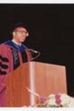 Thomas W. Cole, Jr. stands at the podium at the summer commencement.