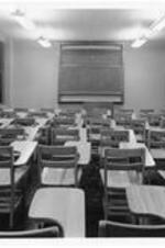 Interior of a classroom with desks and a chalkboard in Dean Sage Hall.