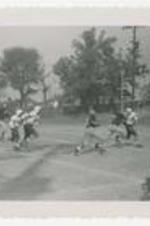 Football players run on a football field.