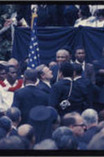 Martin Luther King, Sr. (at center, wearing glasses) and a crowd of attendees gather around the casket of Martin Luther King, Jr. (at right) during the funeral procession in Atlanta, Georgia.