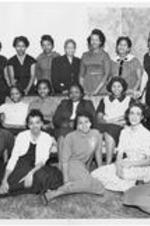 A group of women gather around a couch in a living room. Mrs. Harry V. (Selma) Richardson, seated, lower left. Written on verso: Gammon Theological Seminary. The Gammon Women's Fellowship.