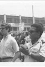 Two unidentified members of the press are shown in the foreground while Coretta Scott King and Leonard Woodcock are shown marching in the background. Written on accompanying document: Mrs. Coretta King and Mr. Woodcock -who replaced Walter Reuther.