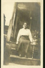 A woman sitting on a porch. Written on verso: Williamsbert on the porch Sept. 1920..