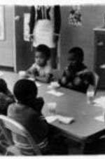 Unidentified children sit around a table praying.
