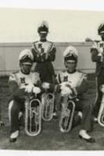 Outdoor group portrait of 5 young men wearing marching band uniforms, view of tubas.