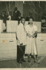 An unidentified couple stand near a stage at an event.