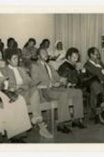 Reverend Jesse Jackson and President Elias Blake Jr. sit, with other men and women in arm chairs at commencement.