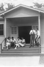 Exterior of a temporary class building with students sitting and standing on the steps out front. Written on verso: Temporary class building, 1947, Atlanta University.