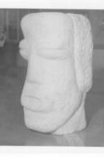 A stone sculpture of a head in African mask style by W. J. Anderson.
