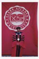 Dr. Thomas Cole poses on the steps of building in front of a banner "Clark Atlanta University" at commencement.