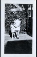 Brailsford R. Brazeal's daughters, Aurelia Erskine and Ernestine Walton Brazeal, hug each other, looking at a garden.