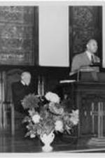 An unidentified man speaks from a pulpit. Written on verso: Inauguration of Dr. Harry Richardson 1949.