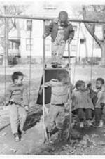 Children play on a playground. Written on verso: Campus children: Billy Shields, Norman Jones, Deon Jones, Kay Jones, William Jr. Meekins.
