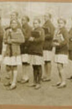 A group of girls hold classbooks and prepare for school.