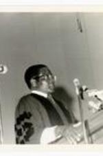 Prime Minister of Zimbabwe Robert Mugabe speaks at podium. Written on verso: September 11, 1983 Zimbabweian Prime Minister Robert Mugabe receives Honorary Doctorate from Morehouse.
