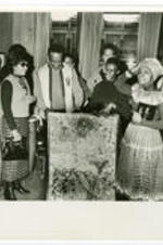 Gwendolyn Brooks stands in a crowd with drums and a painting at a book autograph party. Written on verso: Photo by Normal L. Hunter Autograph Party for Gwen Brooks [Chicago]. '71