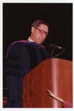 Colin Powell stands at a podium at the summer commencement.