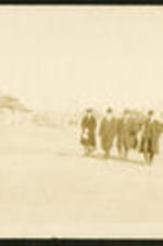 An unidentified woman walks across a field with a group of men.