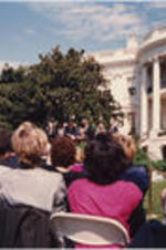 A crowd of people are shown gathered on the White House lawn to witness the signing of the Israel-Palestinian Agreement. President Bill Clinton, Yasser Arafat, and other dignitaries stand on the dais where the signing will occur.