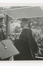 View of a graduate recieving his diploma from Vivian W. Henderson on stage at commencement.