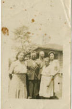 A group of four women and one man stand together outside.